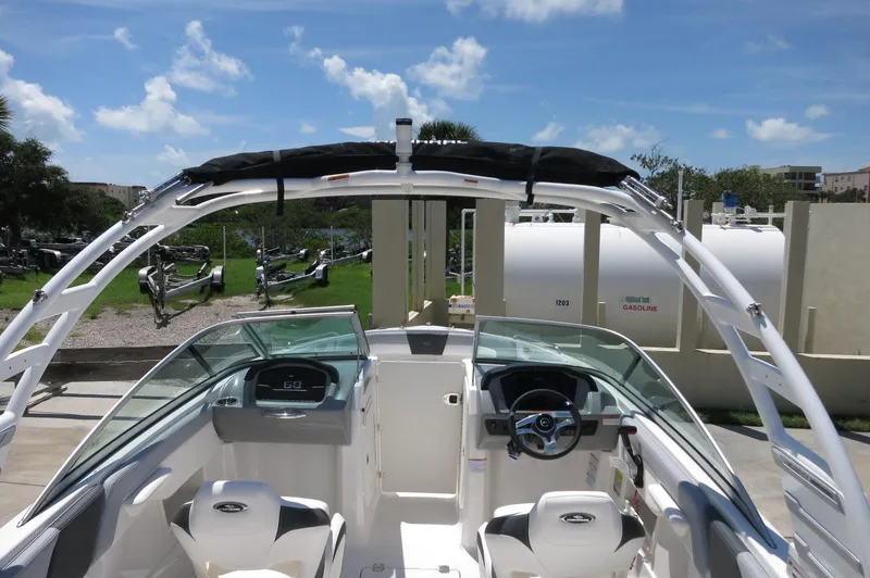 Slide: The Image of 2025 Chaparral 23 SSi OB boat interior with steering wheel and seating, under clear blue sky. - 42
