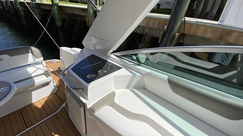 Slide: The Image of 2015 Monterey 295 Sport Yacht interior with seating and kitchenette, docked by water. - 11