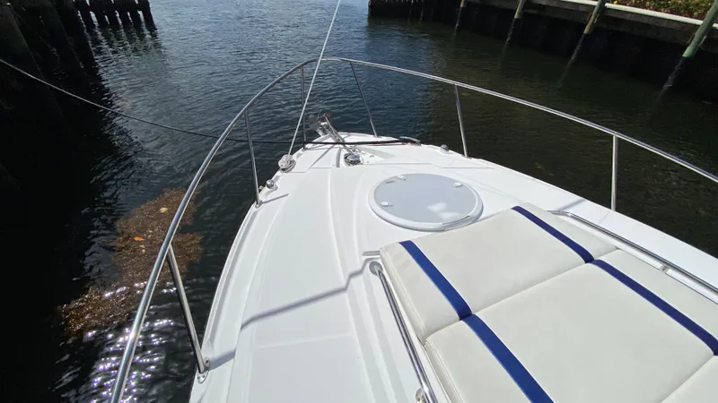 Slide: The Image of 2015 Monterey 295 Sport Yacht bow view with cushioned seating, docked by calm water. - 20