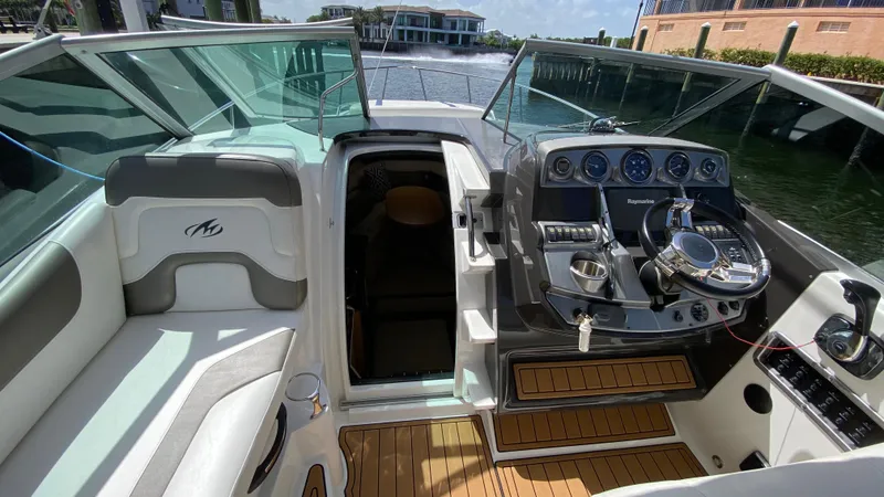 Slide: The Image of 2015 Monterey 295 Sport Yacht cockpit with steering wheel, dashboard, and seating area. - 23