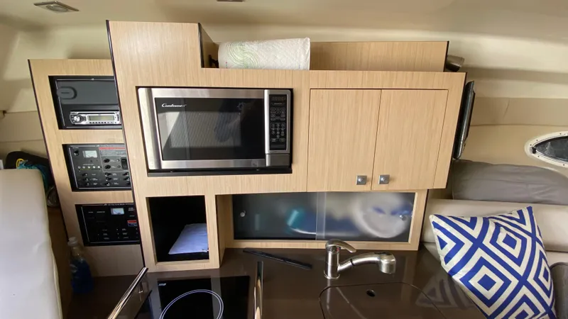 Slide: The Image of 2015 Monterey 295 Sport Yacht interior with microwave, cabinets, and modern kitchen amenities. - 25