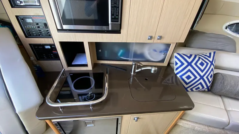 Slide: The Image of Compact kitchen area in a 2015 Monterey 295 Sport Yacht with stove, sink, and microwave. - 26