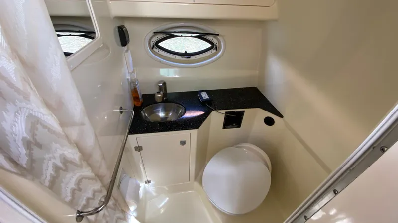Slide: The Image of 2015 Monterey 295 Sport Yacht bathroom with sink, toilet, and porthole window. - 36