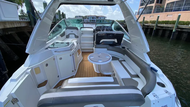Slide: The Image of 2015 Monterey 295 Sport Yacht interior with seating, table, and helm, docked by waterfront. - 5
