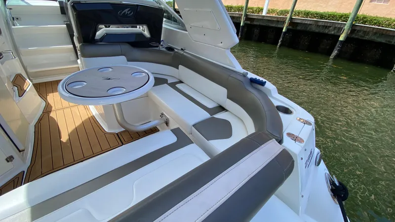 Slide: The Image of 2015 Monterey 295 Sport Yacht interior with seating and table, docked by the water. - 8