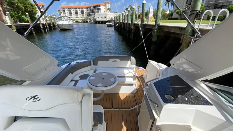 Slide: The Image of 2015 Monterey 295 Sport Yacht interior with seating and table, docked in a marina. - 9