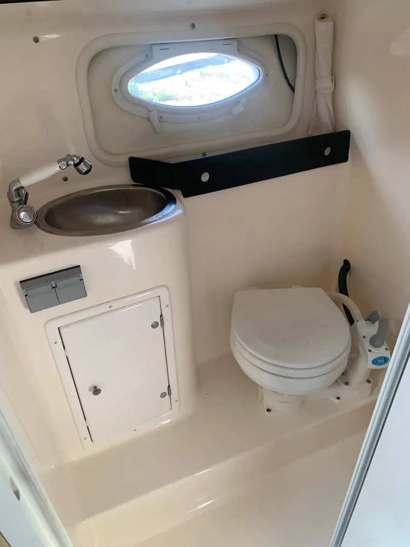 Slide: The Image of Compact bathroom in 2003 Rinker FIESTA VEE 270 boat, featuring sink and toilet. - 12
