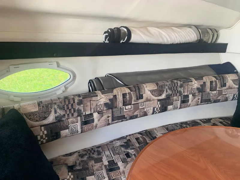 Slide: The Image of 2003 Rinker Fiesta Vee 270 EC cabin interior with patterned seating and wooden table. - 15