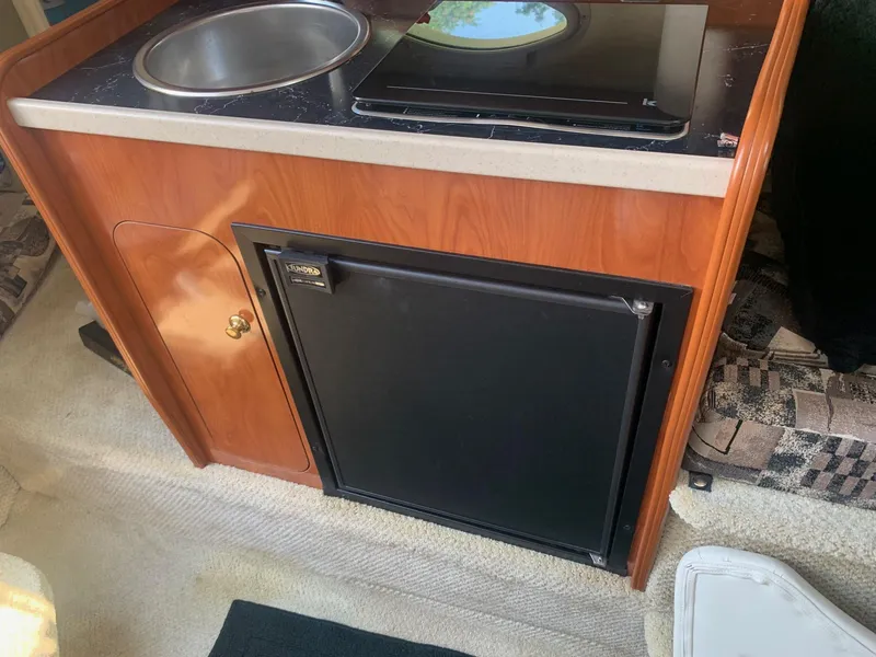 Slide: The Image of 2003 Rinker FIESTA VEE 270 boat kitchenette with sink, stove, and fridge. - 16