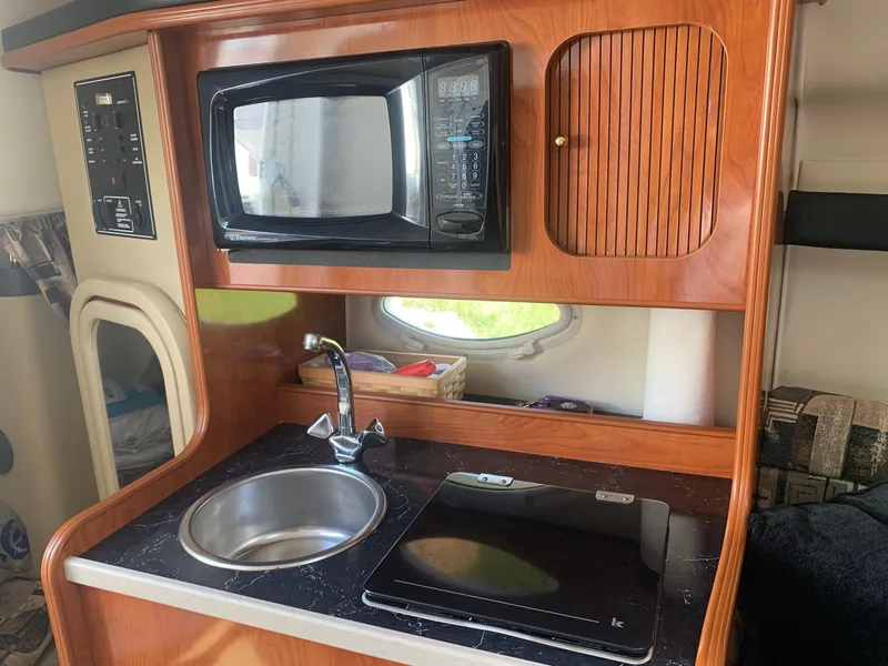 Slide: The Image of 2003 Rinker Fiesta Vee 270 EC kitchenette with microwave, sink, and stove. - 17