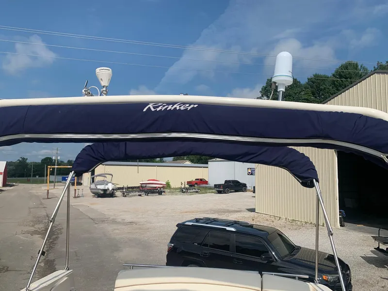 Slide: The Image of 2003 Rinker Fiesta Vee 270 boat with blue canopy, parked near industrial buildings. - 6