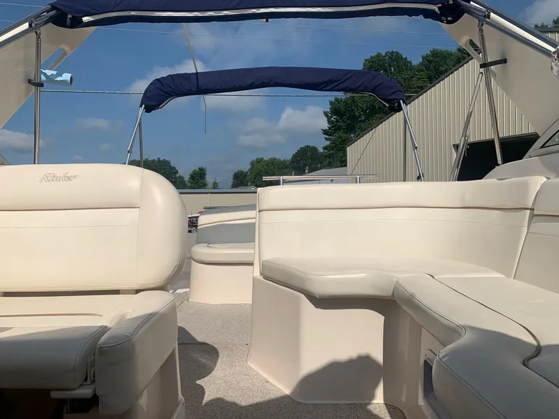 Slide: The Image of 2003 Rinker Fiesta Vee 270 EC boat interior with beige seating and blue canopy. - 9