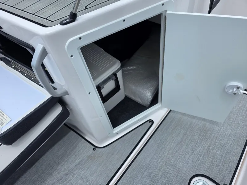 Slide: The Image of 2025 Yamaha Boats AR195 storage compartment with open door, revealing interior space. - 10