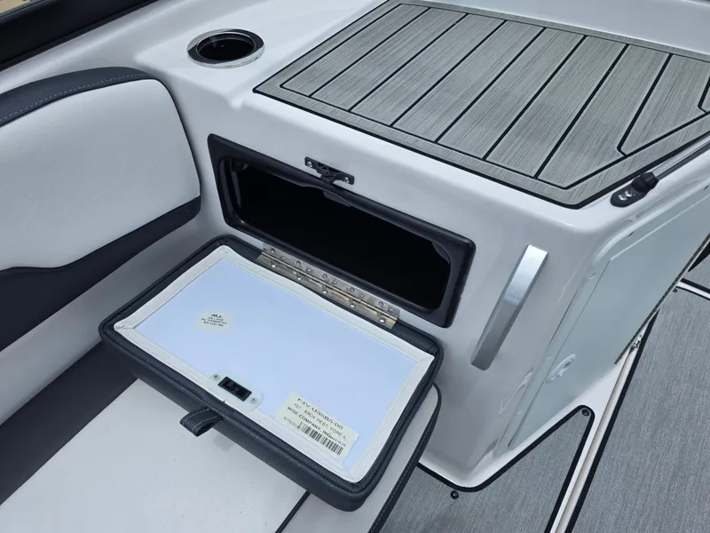 Slide: The Image of 2025 Yamaha Boats AR195 interior storage compartment with open hatch and cup holder. - 7