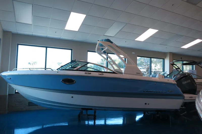 Slide: The Image of 2025 Chaparral 250 OSX boat displayed indoors, featuring sleek blue and white design. - 2