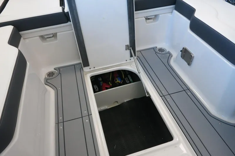 Slide: The Image of 2025 Chaparral 250 OSX boat interior with open storage compartment and sleek gray flooring. - 24