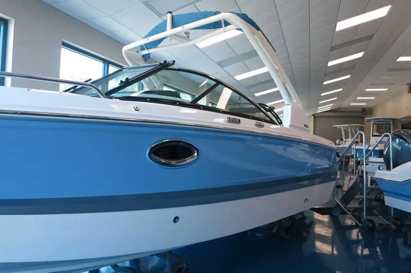Slide: The Image of 2025 Chaparral 250 OSX boat in showroom, featuring sleek blue and white design. - 3