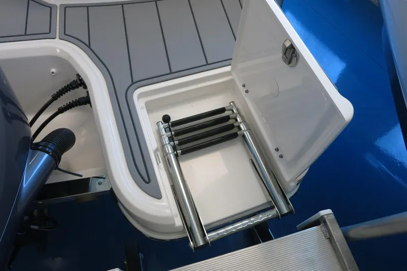 Slide: The Image of 2025 Chaparral 250 OSX boat ladder compartment with open hatch and stainless steel ladder. - 6
