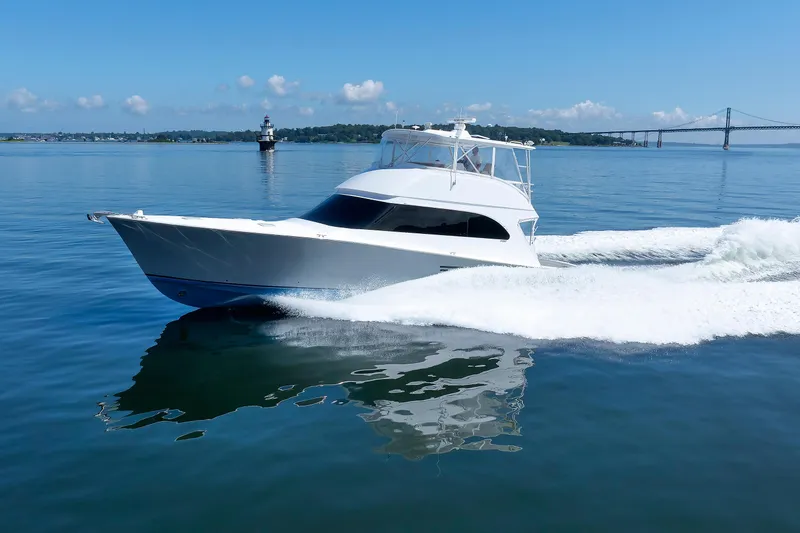 Slide: The Image of 2002 Post Convertible 56 yacht cruising on calm waters near a lighthouse and bridge. - 10