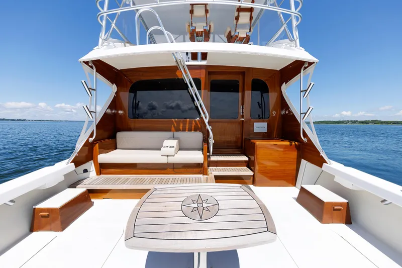 Slide: The Image of Luxury yacht deck with wooden accents, featuring seating and a table, under clear blue skies. - 25