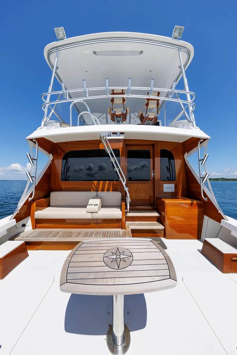 Slide: The Image of Luxury 2002 Post Convertible 56 yacht with elegant wooden deck and seating under clear blue sky. - 26