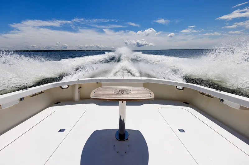 Slide: The Image of 2002 Post Convertible 56 boat cruising on open water, leaving a wake under a clear blue sky. - 32