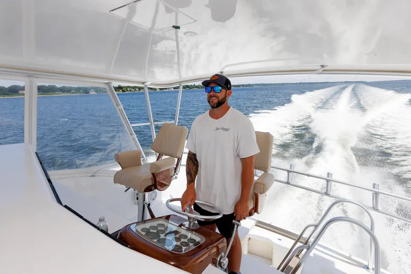 Slide: The Image of Man steering a 2002 Post Convertible 56 yacht on open water. - 40