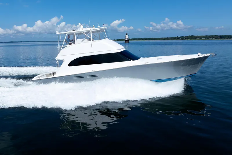 Slide: The Image of A 2002 Post Convertible 56 yacht cruising on calm waters near a lighthouse. - 5