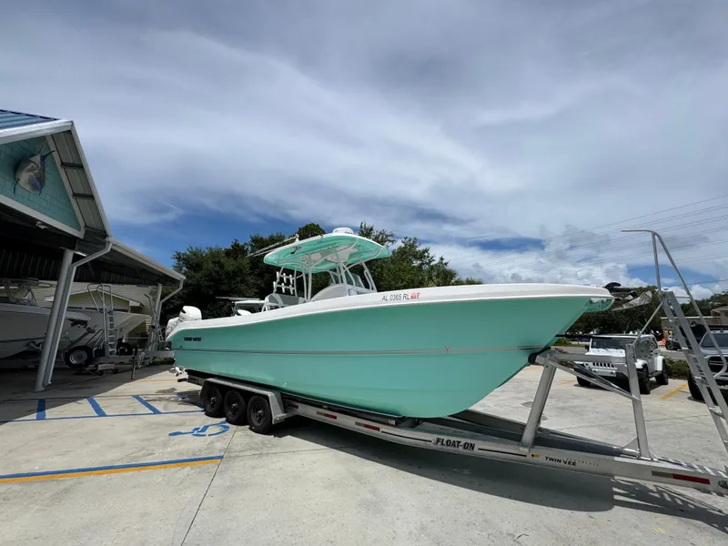 Slide: The Image of 2020 Twin Vee 310 CC GF boat on trailer, parked outdoors under cloudy sky. - 10