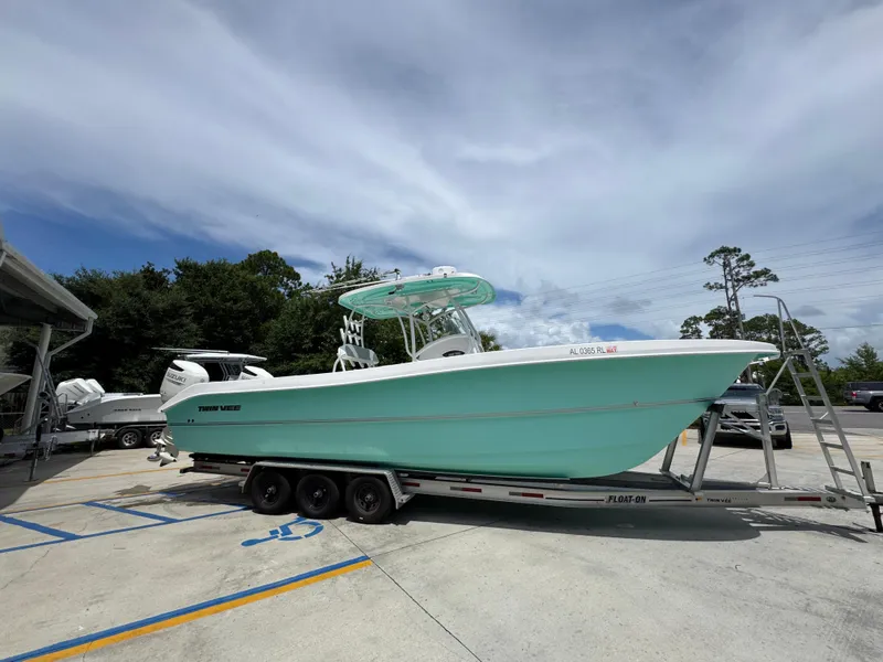 Slide: The Image of 2020 Twin Vee 310 CC GF boat on trailer, parked outdoors under a cloudy sky. - 11