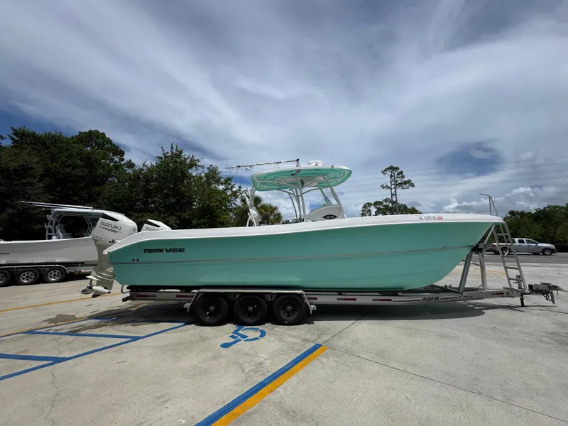 Slide: The Image of 2020 Twin Vee 310 CC GF boat on trailer in parking lot, under cloudy sky. - 12