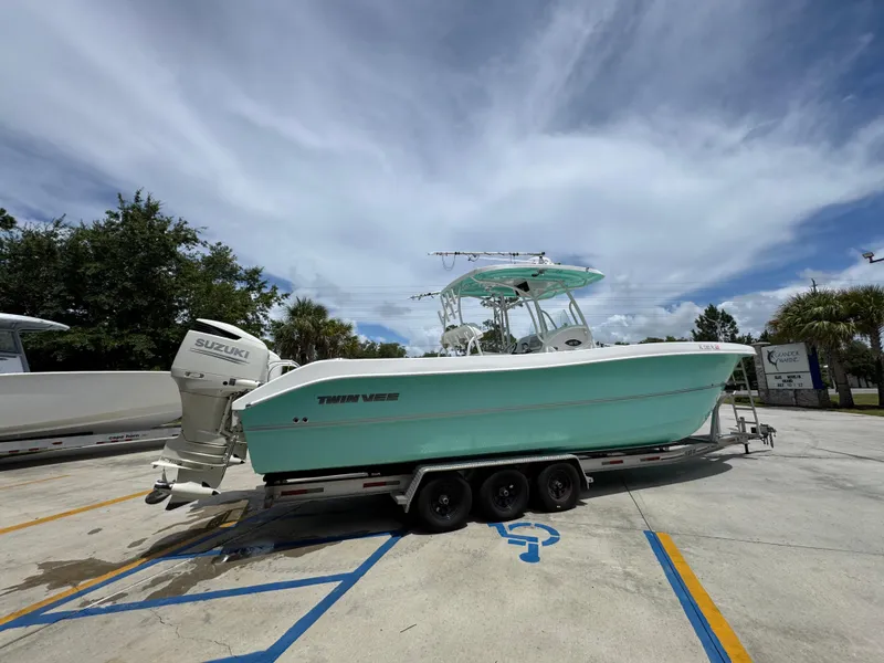 Slide: The Image of 2020 Twin Vee 310 CC GF boat on trailer, parked outdoors under a cloudy sky. - 13
