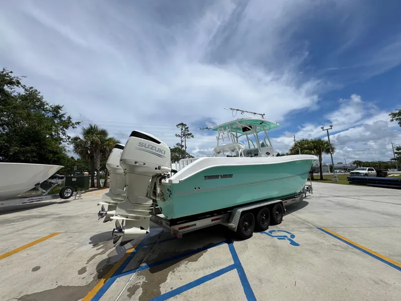 Slide: The Image of 2020 Twin Vee 310 CC GF boat with Suzuki engines on a trailer, parked outdoors. - 14