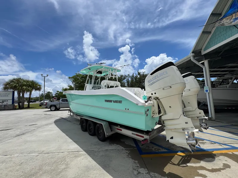 Slide: The Image of 2020 Twin Vee 310 CC GF boat on trailer with Suzuki engines, under blue sky. - 19