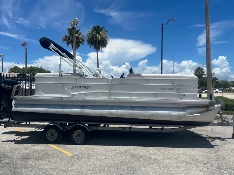 Slide: The Image of 2022 Godfrey SWEETWATER 2286 SFL pontoon boat on trailer under blue sky. - 1