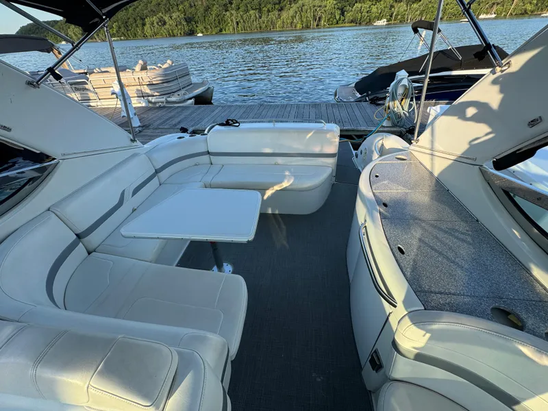 Slide: The Image of 2006 Formula 370 SS boat interior with white seating and table, docked by a scenic lake. - 11