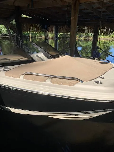 Slide: The Image of 2021 Scout 215 Dorado boat under a wooden dock, featuring a beige cover. - 13