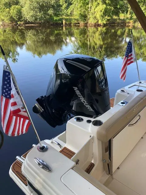 Slide: The Image of 2021 Scout 215 Dorado boat with Mercury engine and American flags on a calm lake. - 14