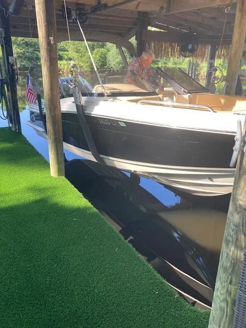 Slide: The Image of 2021 Scout 215 Dorado boat docked under a wooden shelter with artificial grass. - 23