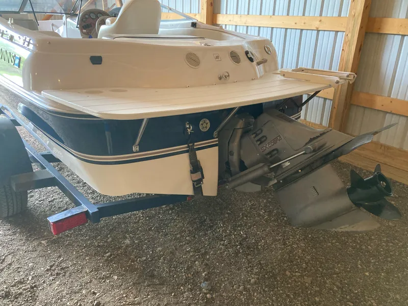 Slide: The Image of 1998 Four Winns Horizon QX boat in storage, showing rear view and outboard motor. - 4