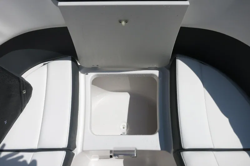 Slide: The Image of 2025 Chaparral 270 OSX boat interior storage compartment with white cushioned seating. - 17
