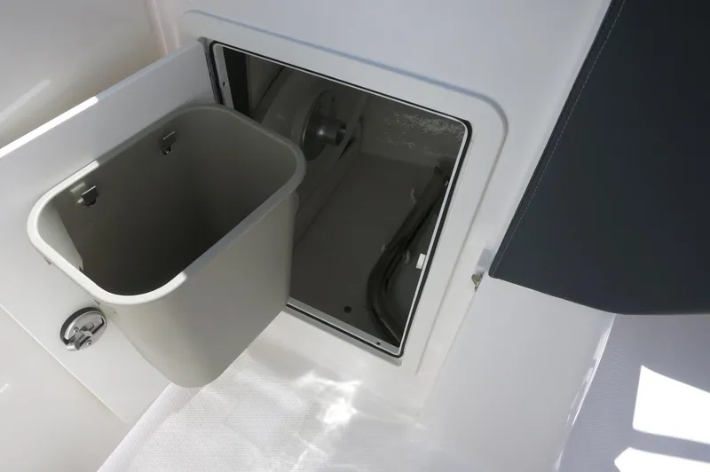 Slide: The Image of 2025 Chaparral 270 OSX boat storage compartment with trash bin. - 23