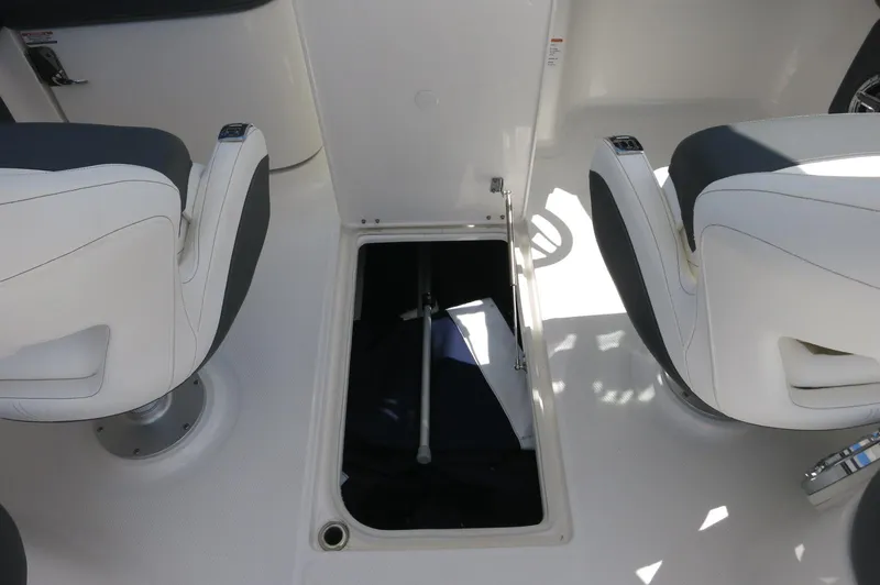 Slide: The Image of 2025 Chaparral 270 OSX boat interior with open storage compartment between seats. - 30