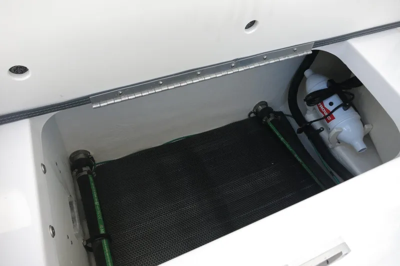 Slide: The Image of Storage compartment in 2025 Chaparral 270 OSX boat, featuring equipment and hoses. - 32