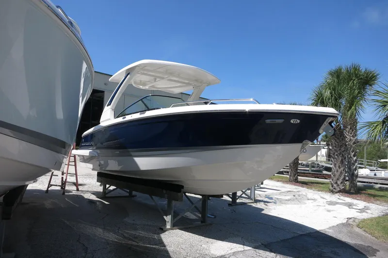 Slide: The Image of 2025 Chaparral 270 OSX boat displayed outdoors, blue hull, sunny day, palm trees nearby. - 4