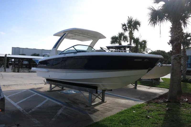 Slide: The Image of 2025 Chaparral 270 OSX boat displayed outdoors on a stand, surrounded by palm trees. - 42