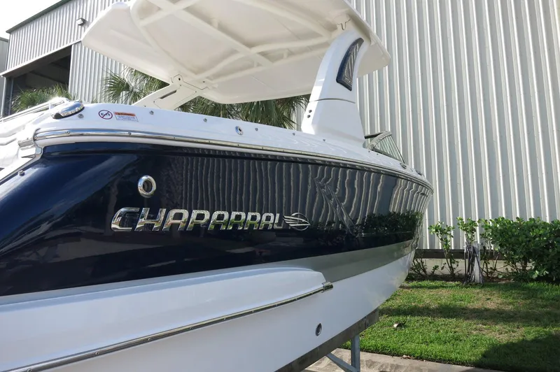 Slide: The Image of 2025 Chaparral 270 OSX boat, sleek design, docked near a metal building. - 49