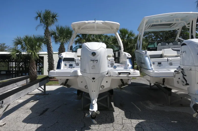 Slide: The Image of 2025 Chaparral 270 OSX boat with dual engines, parked outdoors under clear blue sky. - 5