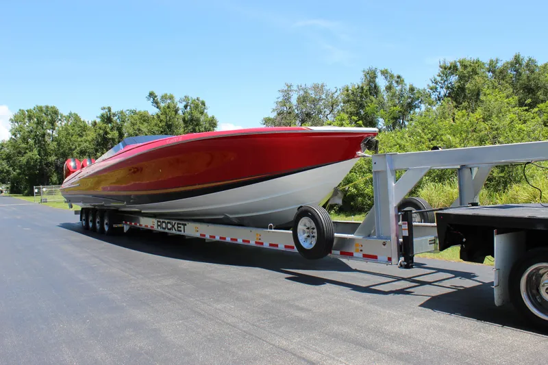 Slide: The Image of 2023 Nor-Tech 55 Flyer boat on trailer, vibrant red, parked on sunny road. - 21