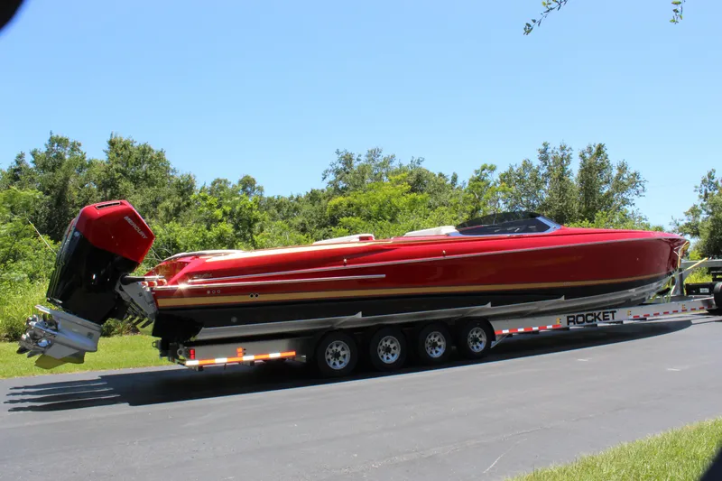 Slide: The Image of 2023 Nor-Tech 55 Flyer boat on trailer, vibrant red, parked on road. - 23